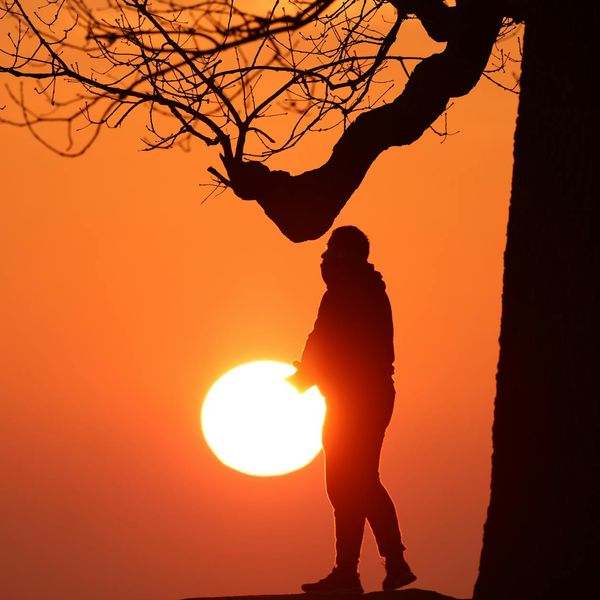 Silhouette of a man stretching against a sunrise, symbolizing harmony.